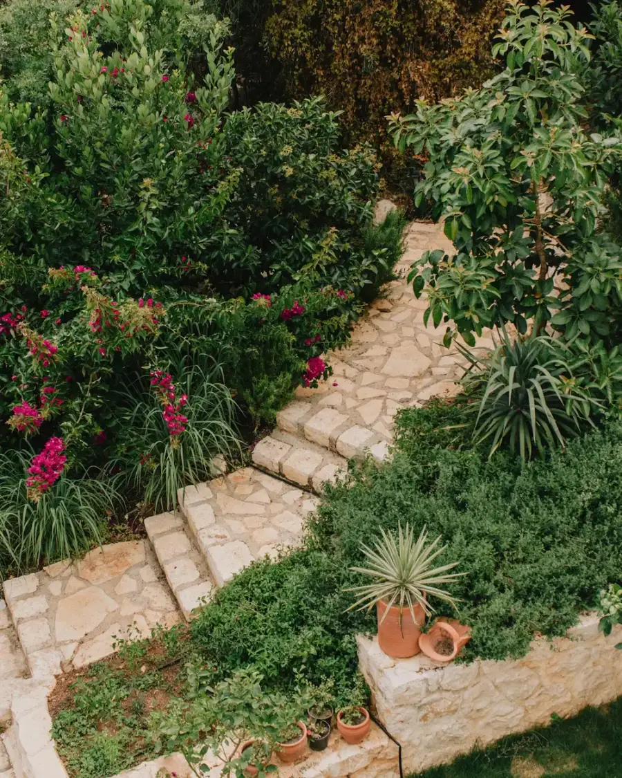 A redesigned garden with stone steps, lush planting beds, and pots
