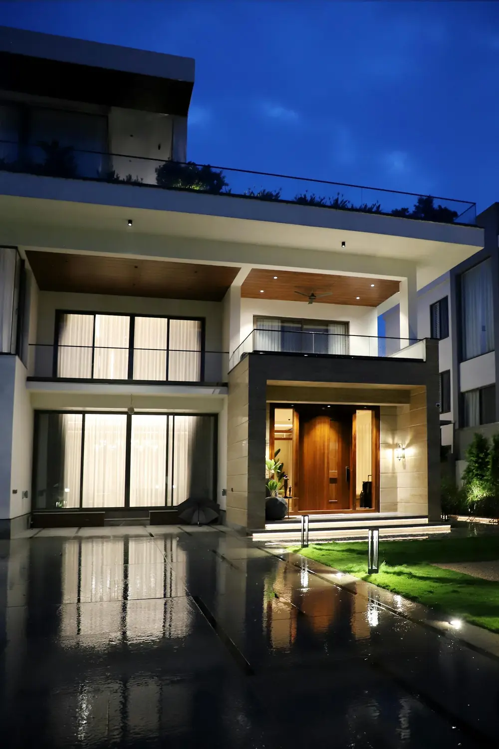 Architectural waterfront home lit at dusk