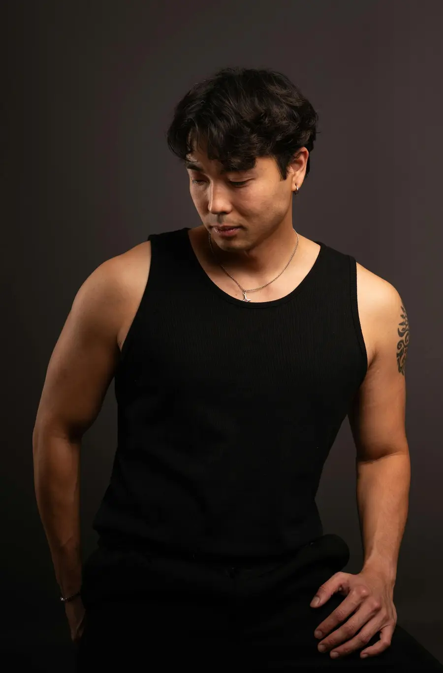 Studio portrait of a man in black against a dark backdrop